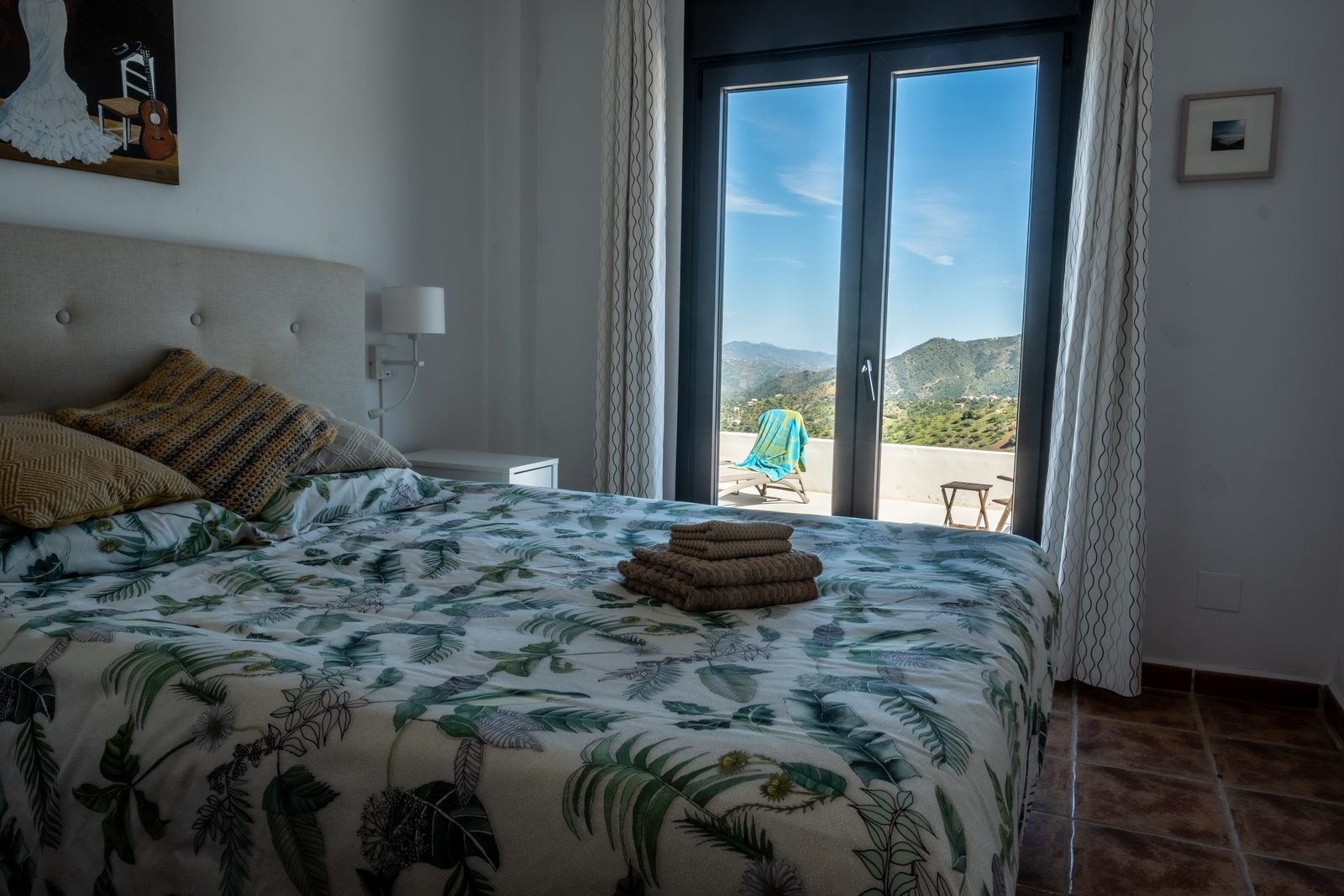 Master bedroom met opgemaakt bed en openslaande deuren naar het vergrote terras