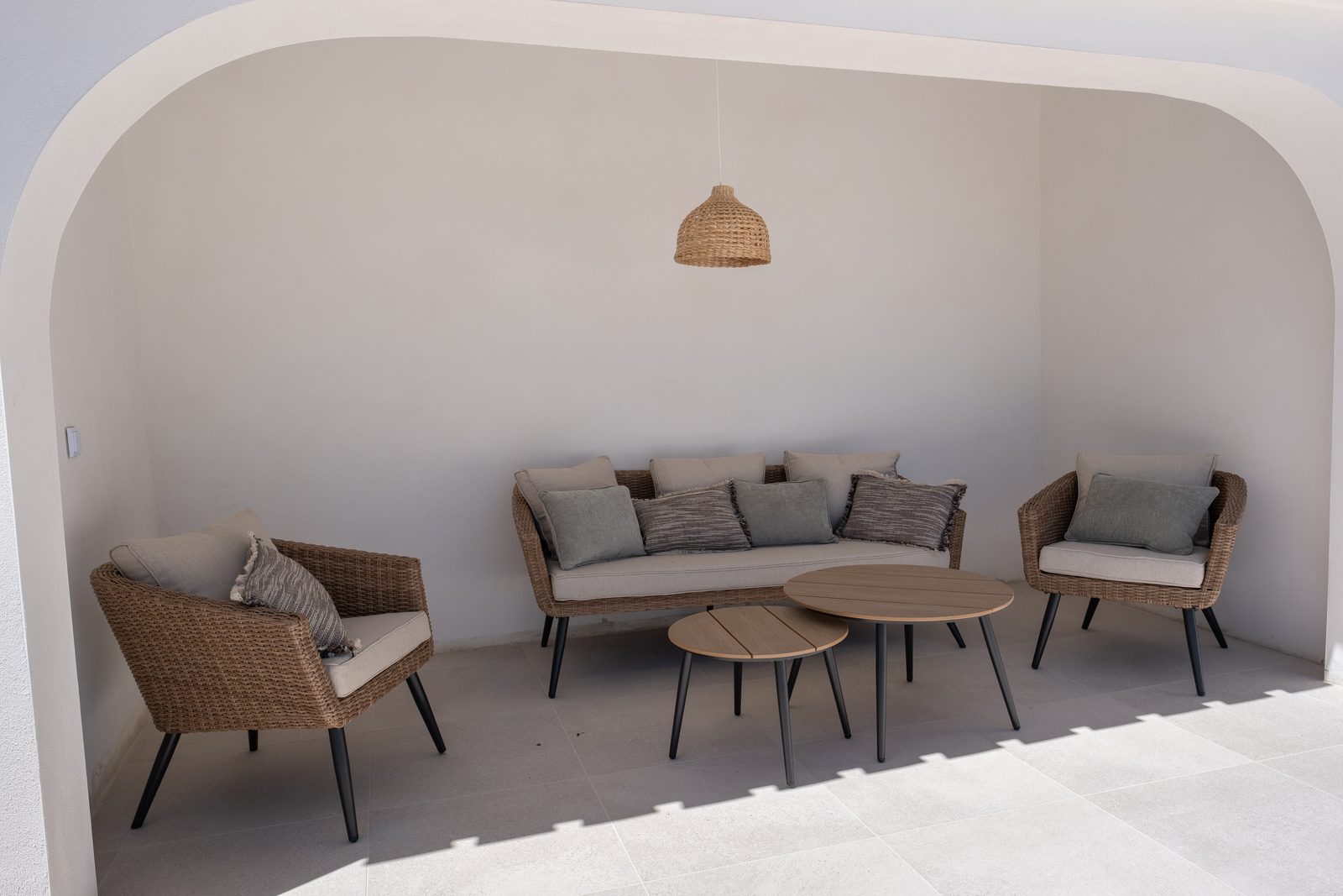 Overdekte patio met loungeset onder een gepleisterde boog