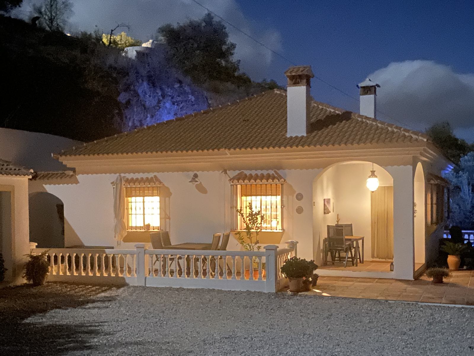 De witte villa in bungalowstijl in het avondlicht, met verlichte veranda
